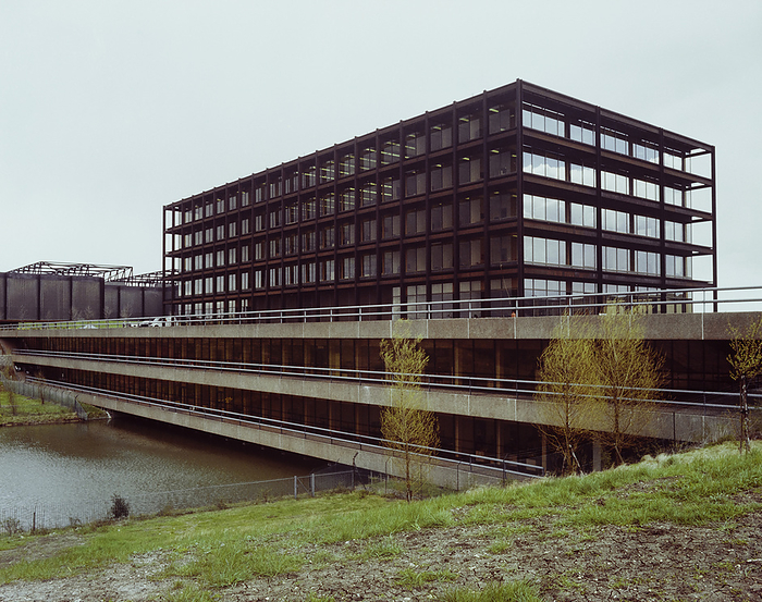 WD and HO Wills, Whitchurch Lane, City of Bristol, 15 06 1979. Creator: John Laing plc. WD and HO Wills, Whitchurch Lane, City of Bristol, 15 06 1979. The podium building, bridging the artificial lake, and the office block above it at the Wills tobacco factory at Hartcliffe, Bristol. Both the office building and the factory itself were constructed from Cor Ten steel frames, Cor Ten steel was pre weathered to produce a russet brown patina which would in theory harmonise with the landscaping.  The use of Cor Ten steel for the bold exposed frame of the office building is given as one of the principal justifications awarding it Grade II listed status in May 2000.  The building was converted into flats in around 2007 whilst the factory itself had been demolished in 1999. The podium building that the office block sits above housed various amenities for the factory employees, shops, restaurants and even a cinema.  This was in response to a survey that Wills undertook and to compensate for the out of town location of the new factory compared to the Southville and Bedminster sites that it replaced.