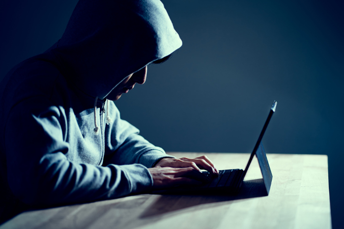 Male hacker writing code on a laptop