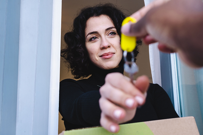 Smiling woman taking keys from realtor in new house, Photo by ANTHONY PHOTOGRAPHY