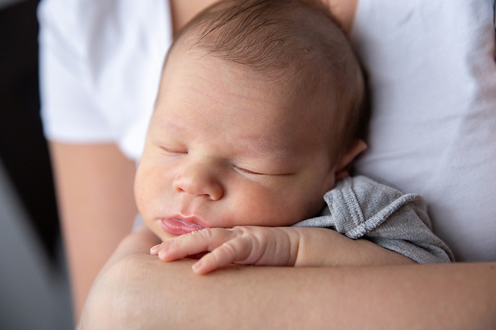 Portrait of a sleeping baby in his mother's arms