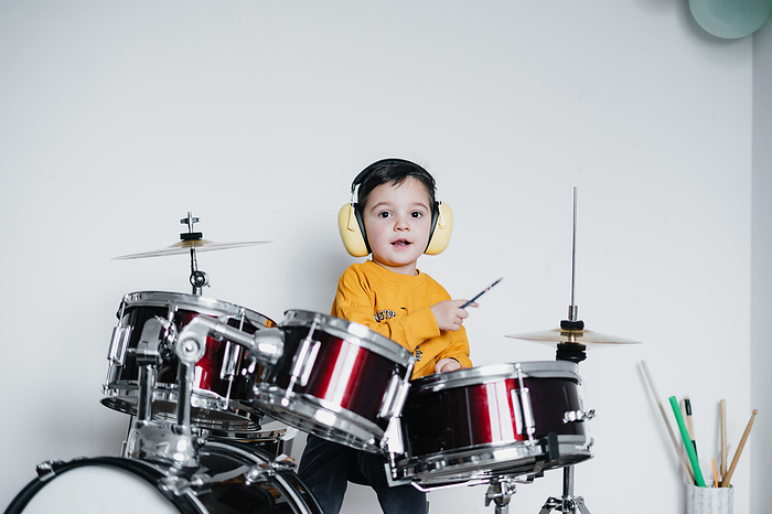 Kid wearing ear protective headphones while playing drums