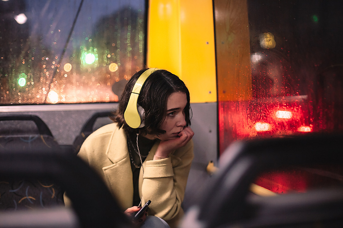 Young woman listening music in headphones traveling in trolley bus