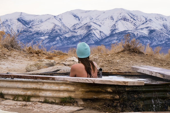 Female relaxing in hot springs with mountain views