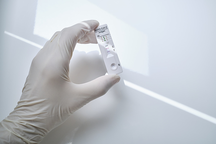 Hand holding rapid diagnostic device with COVID-19 positive results, Photo by Philipp Nemenz