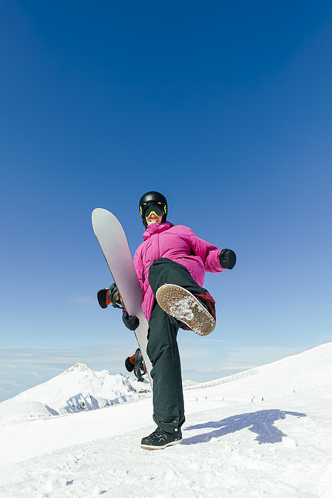 Man with snowboard kicking standing on snowy mountain
