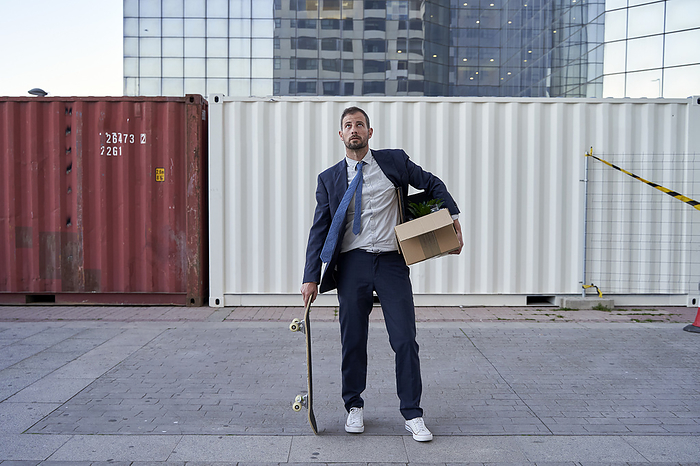 Businessman with skateboard and office belongings in city