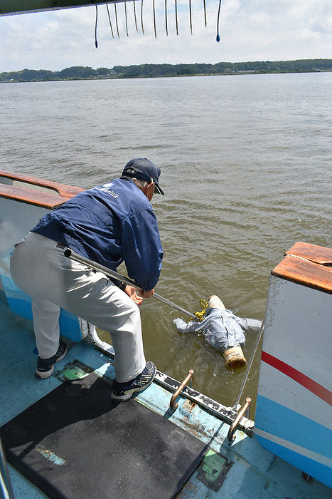Training participants pulling up a doll in case of a person falling into the water. Training participants pull up a doll in case a person falls into the water, on Kasumigaura Lake, May 23, 2022  photo by Shigetaka Niwagi .