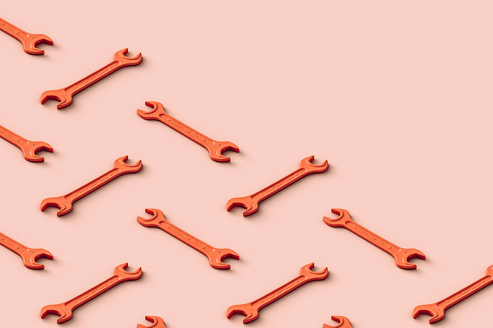 Three dimensional pattern of rows of orange colored wrenches flat laid against beige background