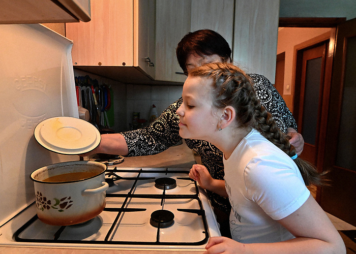 Uliana, a grandchild, smells the soup prepared by Irina Kobubasa  back . Grandson Uliana smells the soup prepared by Irina Cobbasa  back  in Edinet, May 27, 2022  photo by Naohiro Yamada.