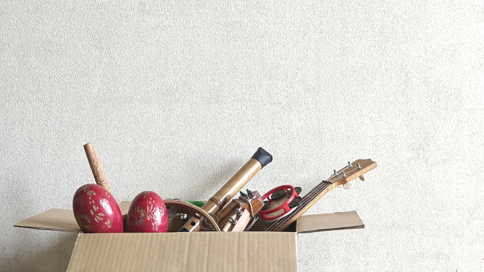 Lots of old musical instruments and toys in cardboard boxes_white wall background