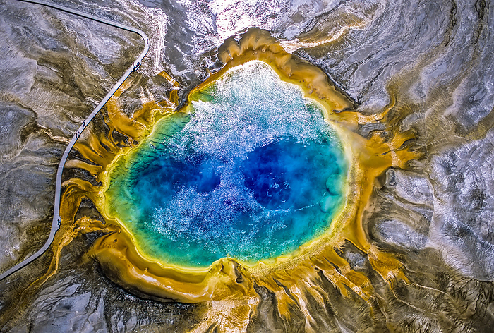 Grand Prismatic Spring is one of the largest and most beautiful examples of a common hydrothermal feature in Yellowstone National Park and one of the largest hot springs in the United States. The prismatic, colorful features come from several sources; the deep blue in the center is the clear super-heated water circulating up from the subterranean heat source and shows a pair of convection currents, like a pair of eyes. As the water cools at the edges of the pool and on the sinter terraces, bacteria and algae produce the rainbow of colors. This hot spring was specifically mentioned in Osborne Russell's Journal of a Trapper, by the name of Boiling Lake, which apparently was a name given to it by Rocky Mountain fur trappers in the 1830s, in Yellowstone National Park; Wyoming, United States of America, Photo by Tom Murphy / Design Pics