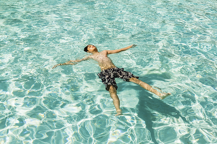 A boy floating on his back in a swimming pool at a resort in Ka'anapali; Ka'anapali, Maui, Hawaii, United States of America, Photo by LJM Photo / Design Pics