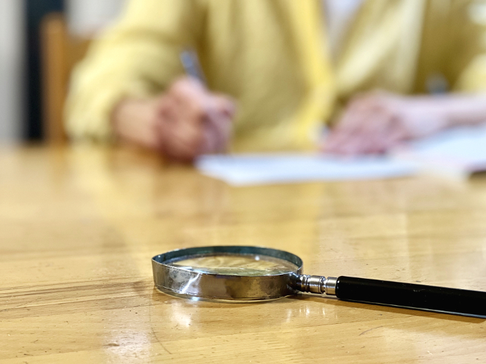 Blurred hand of elderly woman writing behind a magnifying glass