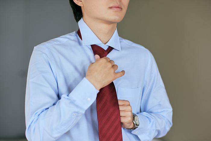 A man's hand tightening a tie