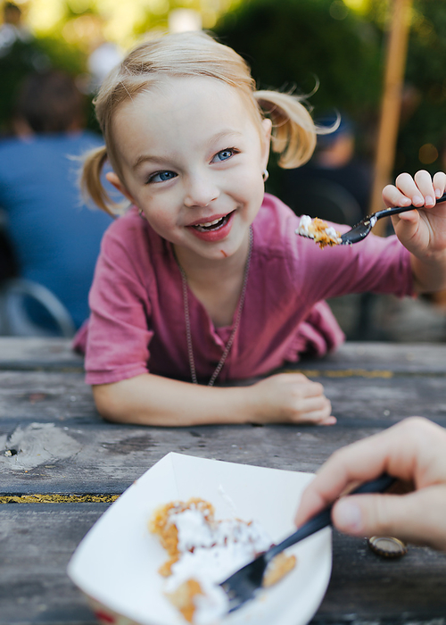 young girl sharing a treat at a picnic table