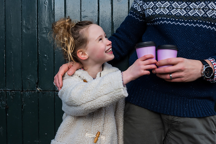 child holding take away hot drink cheers to her dad