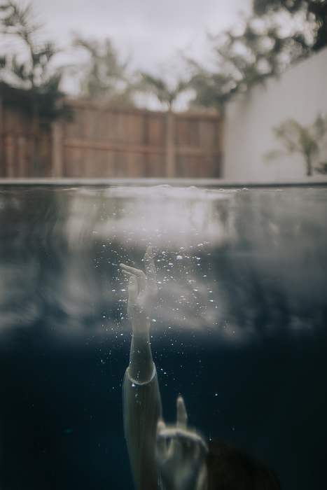 underwater hands reaching the top of pool with bubbles