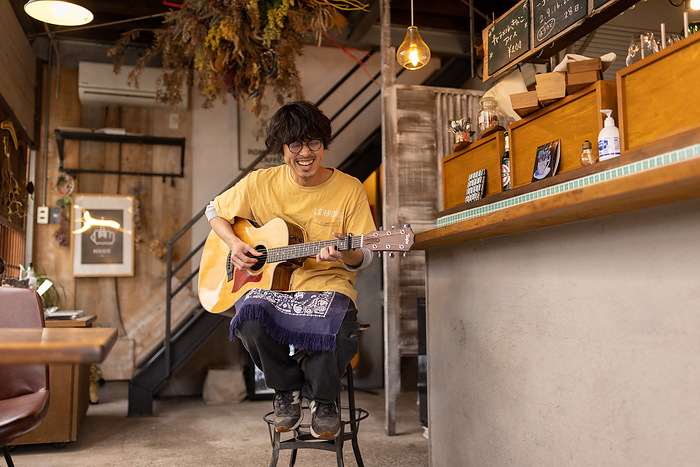 Japanese man playing guitar Junichi Imoto, who lives in Tamaki Town, Mie Prefecture, is a musician under the name Jun Lenon and the owner of the restaurant  acatoki,  where he also cooks.  Photo taken March 2022 