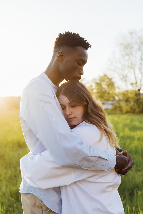 Young couple hugging each other in nature on sunny day