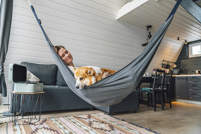 Woman relaxing on hammock with dog at home