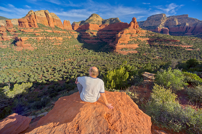 A man sitting on the top of Mescal Mountain overlooking Deadmans Pass in Sedona Arizona. A man sitting on the top of Mescal Mountain overlooking Deadmans Pass in Sedona, Arizona, United States of America, North America, Photo by Steven Love