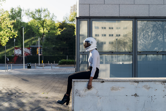 Businesswoman wearing astronaut helmet by office building