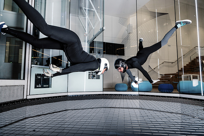 Woman with friend flying in wind tunnel