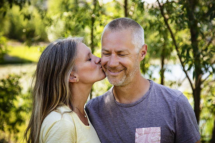 Portrait of a mature couple together outside with woman kissing her husband's cheek; Edmonton, Alberta, Canada, Photo by LJM Photo / Design Pics