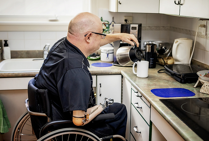 Man with double limb amputations pouring coffee in the kitchen at home; St. Albert, Alberta, Canada, Photo by LJM Photo / Design Pics
