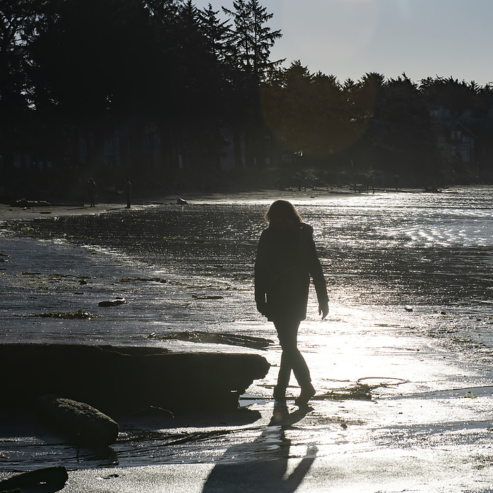 Woman walks on the sunlit sand of Cox Bay Beach on the west coast of Vancouver Island; British Columbia, Canada, Photo by Keith Levit / Design Pics