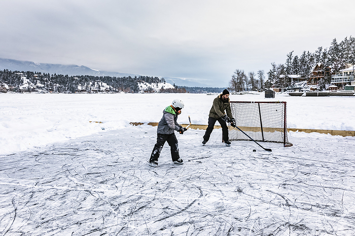 Father and his son playing hockey on a frozen Windermere Lake during the winter, Windermere Lake Provincial Park; Invermere, British Columbia, Canada, Photo by LJM Photo / Design Pics