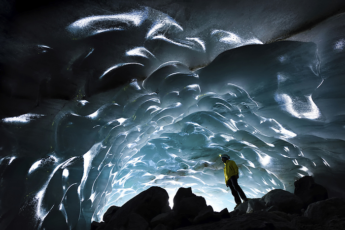 A cave explorer and glaciologist admiring the fine sculptured walls of blue ice inside the cave., Photo by Robbie Shone / Design Pics