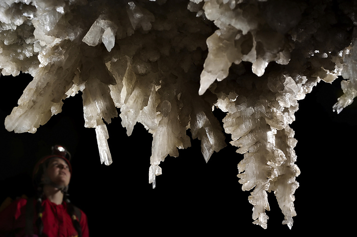 A speleologist studies gypsum formations as they cling to the roof of an obscure undercut in Sang Wang Dong., Photo by Robbie Shone / Design Pics