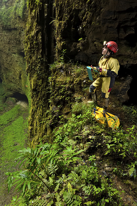 A speleologist on a small ledge overlooking the vast floor surface of Niubizi Tian Keng in the Er Wang Dong cave system., Photo by Robbie Shone / Design Pics