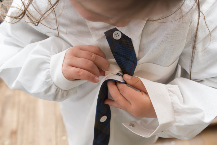 A child buttoning a shirt