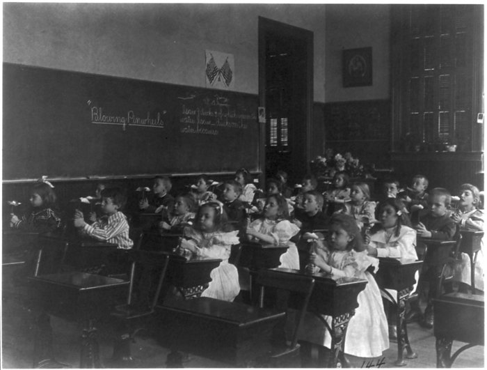 Children in a classroom blowing pinwheels in a Washington, D.C., grade school,  1899  . Creator: Frances Benjamin Johnston. Children in a classroom blowing pinwheels in a Washington, D.C., grade school,  1899  .