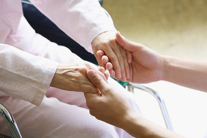 Senior woman and caregiver holding hands
