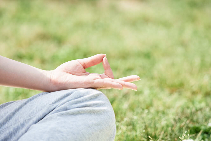 A woman's hand meditating in lush green nature