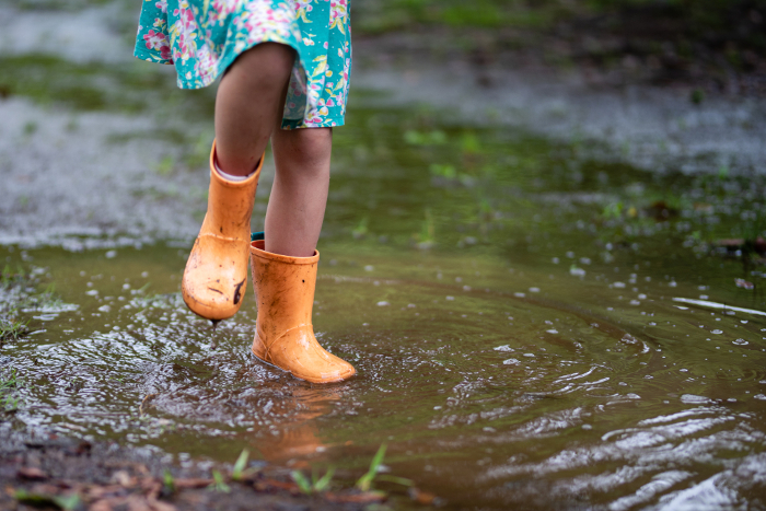 A child playing in a puddle with boots on