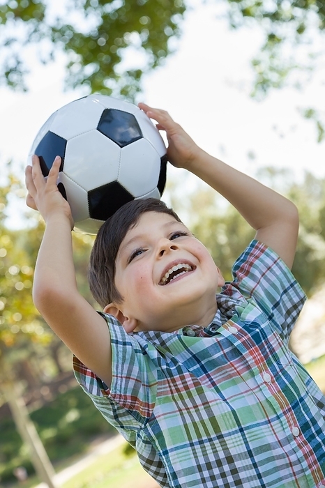 Cute young boy playing with soccer ball outdoors in the park, Photo by Andy Dean