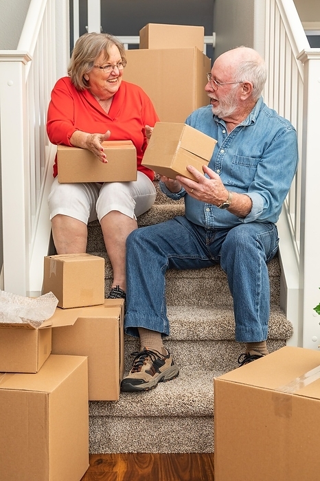 Senior couple resting on stairs surrounded by moving boxes, Photo by Andy Dean
