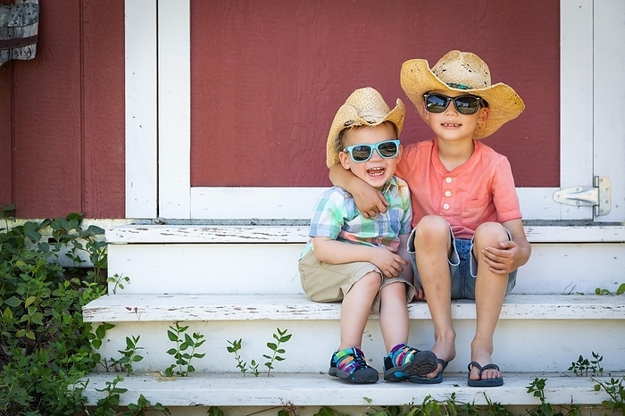 mixed-race chinese and caucasian young brothers having fun wearing sunglasses and cowboy hats, Photo by Andy Dean