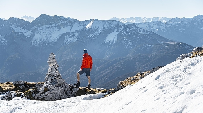Mountaineer next to a cairn, in front of snowy mountains of the Rofan, hiking trail to the Guffert with first snow, in autumn, Brandenberg Alps, Tyrol, Austria, Europe, Photo by Mara Brandl