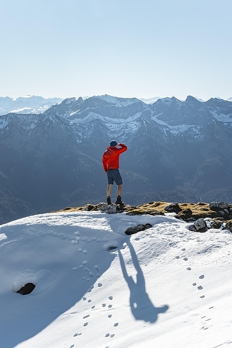 Mountaineer looking into the distance, next to a cairn, in front of snow-covered mountains of the Rofan, hiking trail to the Guffert with first snow, in autumn, Brandenberg Alps, Tyrol, Austria, Europe, Photo by Mara Brandl