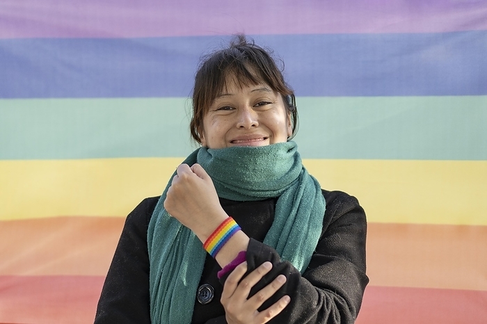 Portrait of a lesbian latin woman wearing lgbt wristband on a rainbow background, Photo by Mariano Gaspar