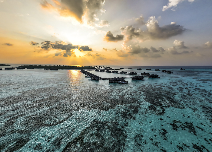 Maldives, North Male Atoll, Lankanfushi, Aerial view of Indian Ocean at sunset with tourist resort bungalows in background