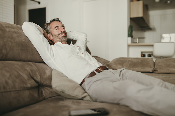 Smiling businessman relaxing on sofa at home