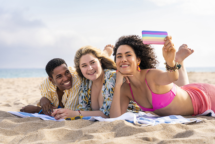 Multiracial friends taking selfie through smart phone at beach