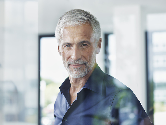 Business people Mature businessman with gray hair seen through glass