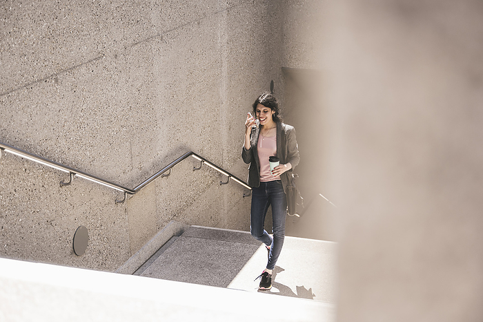 Smiling transgender woman talking on phone climbing steps of subway